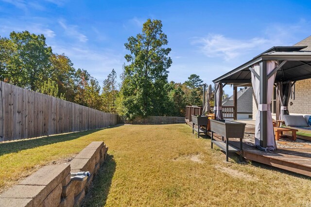 view of yard featuring a gazebo, a wooden deck, and a fenced backyard