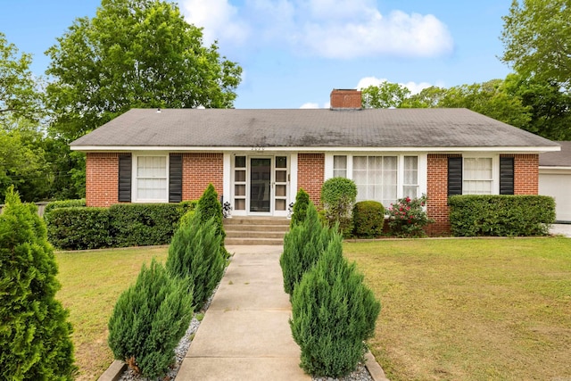 ranch-style home with a chimney, a front lawn, and brick siding