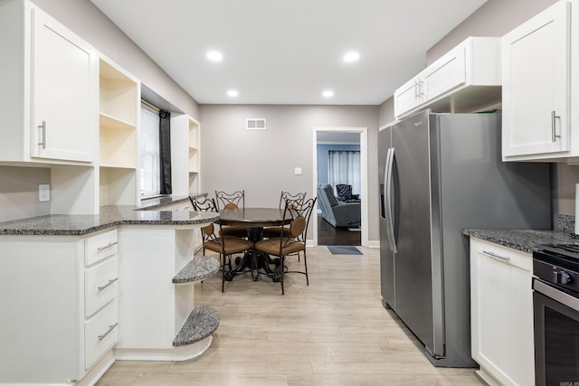 kitchen featuring visible vents, open shelves, white cabinets, light wood finished floors, and dark stone counters