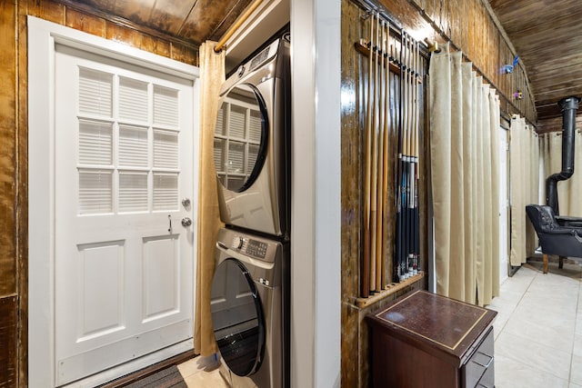 clothes washing area with laundry area, stacked washing maching and dryer, light tile patterned floors, and wooden ceiling
