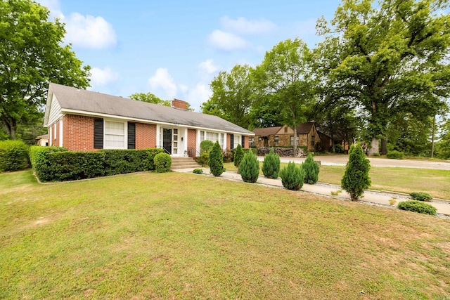 ranch-style house featuring brick siding, a chimney, and a front yard