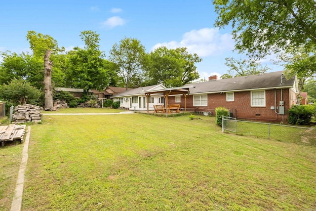 rear view of house with fence, a chimney, a yard, and brick siding