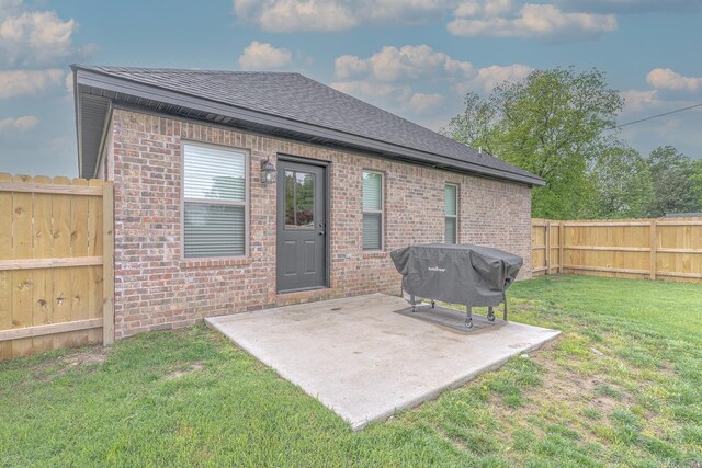 538 Maple St, Trumann, AR 72472 - rear view of house featuring roof with shingles, brick siding, a fenced backyard, a yard, and a patio