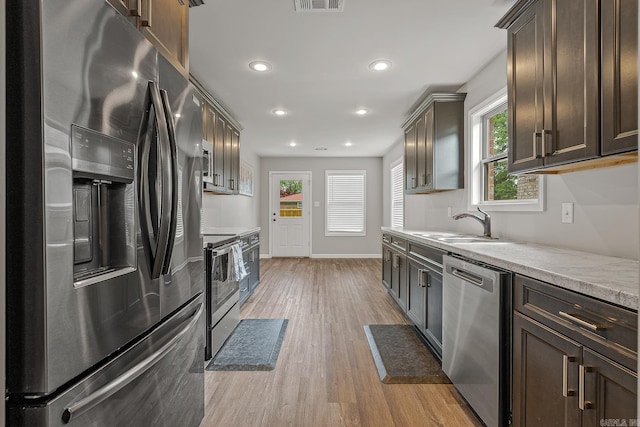 538 Maple St, Trumann, AR 72472 - kitchen with light wood-style floors, appliances with stainless steel finishes, dark brown cabinetry, and a healthy amount of sunlight