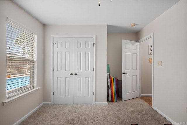 unfurnished bedroom featuring carpet flooring, baseboards, and a closet