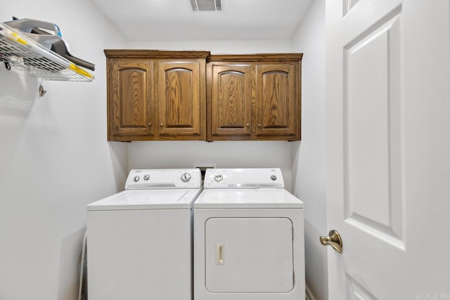 clothes washing area featuring separate washer and dryer, cabinet space, and visible vents