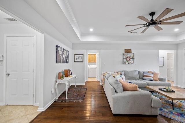 living room featuring a ceiling fan, a tray ceiling, and baseboards