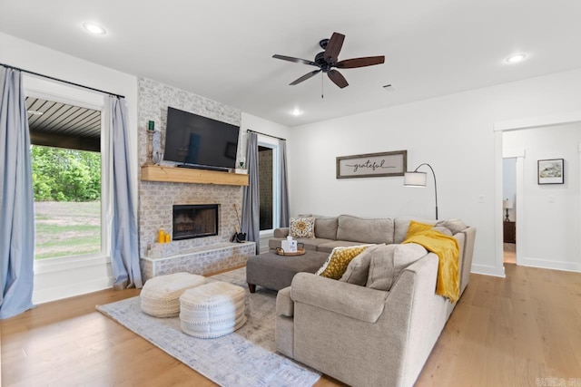 living area featuring baseboards, ceiling fan, a fireplace, and wood finished floors