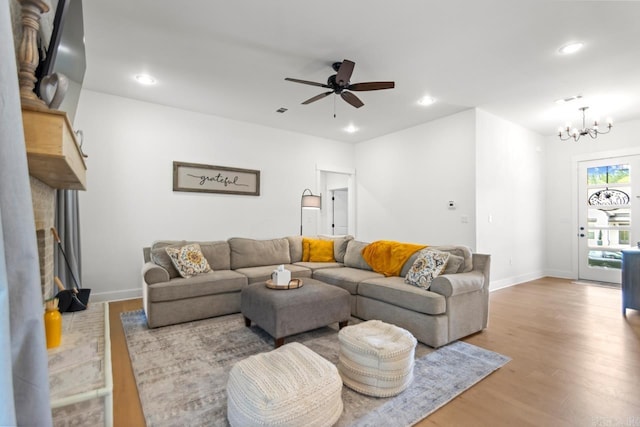living area with wood finished floors, a fireplace, baseboards, recessed lighting, and ceiling fan with notable chandelier
