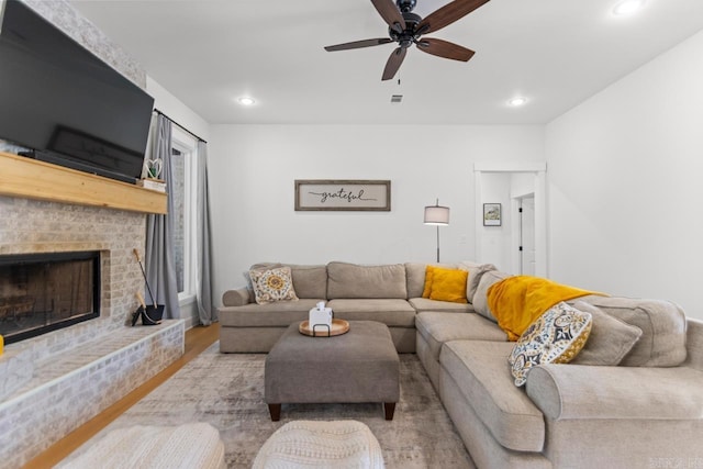 living room with ceiling fan, a brick fireplace, recessed lighting, and wood finished floors