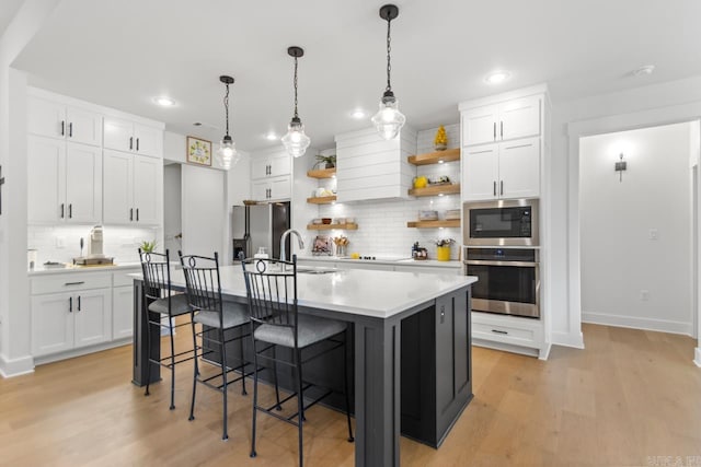 kitchen featuring decorative backsplash, a kitchen bar, appliances with stainless steel finishes, open shelves, and light countertops