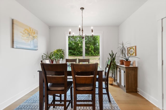 dining room featuring an inviting chandelier, baseboards, and light wood-type flooring