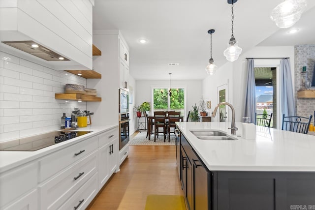 kitchen with open shelves, appliances with stainless steel finishes, a sink, light countertops, and decorative backsplash