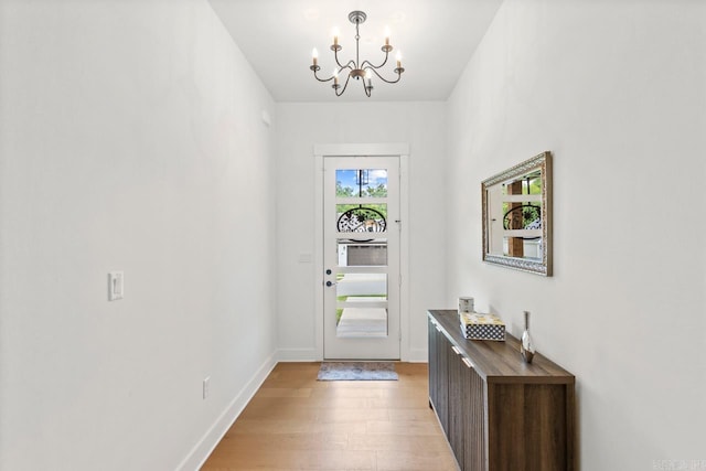 foyer entrance with baseboards, light wood-style flooring, and a chandelier