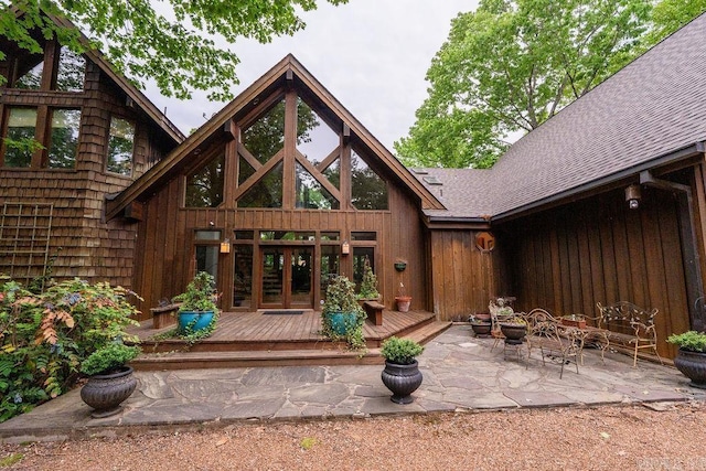 back of property featuring french doors, roof with shingles, a patio area, and a deck