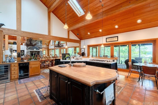 kitchen with beverage cooler, dark cabinets, a center island, wood ceiling, and butcher block counters