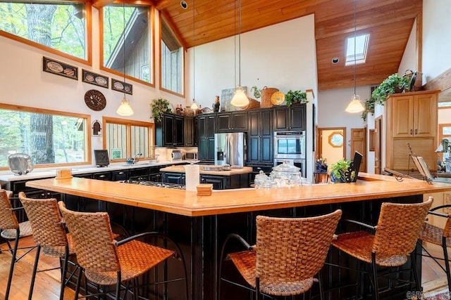 kitchen with high vaulted ceiling, wood ceiling, a spacious island, and appliances with stainless steel finishes
