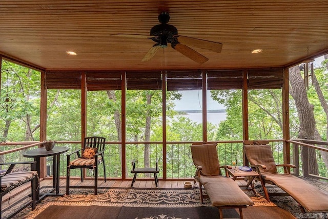 sunroom with a ceiling fan and a water view
