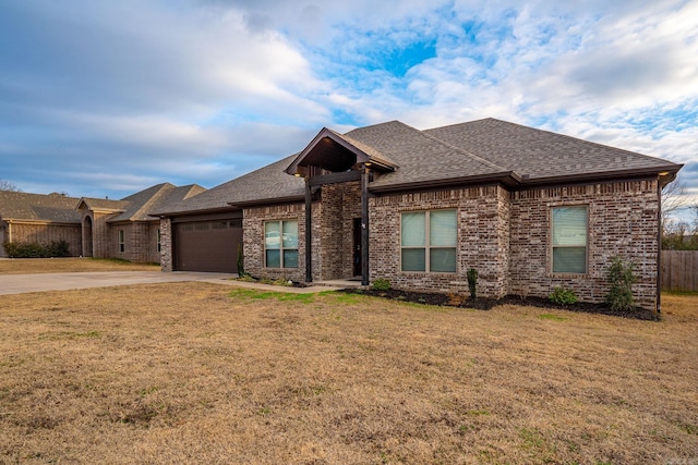 ranch-style home with a garage, a front lawn, roof with shingles, brick siding, and concrete driveway