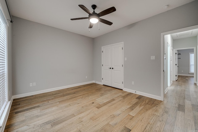 unfurnished bedroom featuring a ceiling fan, baseboards, light wood finished floors, and a closet