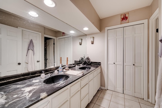 full bath with double vanity, a sink, baseboards, and tile patterned floors