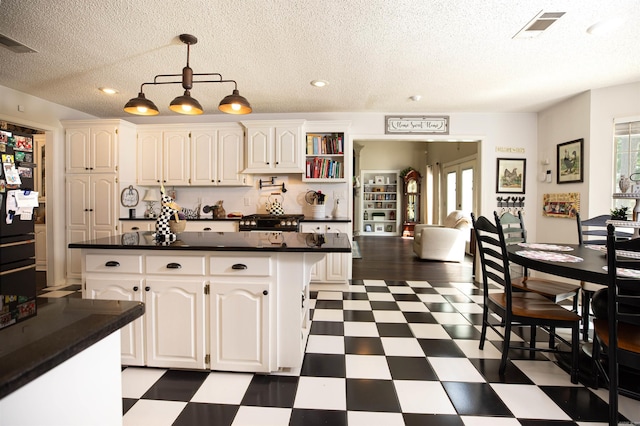 6311 Country Ln, Pine Bluff, AR 71603 - kitchen with visible vents, dark countertops, a textured ceiling, white cabinetry, and dark floors
