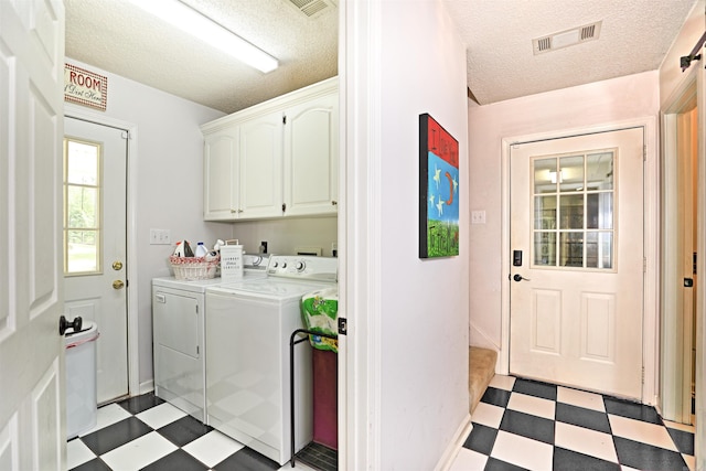 6311 Country Ln, Pine Bluff, AR 71603 - laundry area with visible vents, light floors, washer and clothes dryer, a textured ceiling, and cabinet space