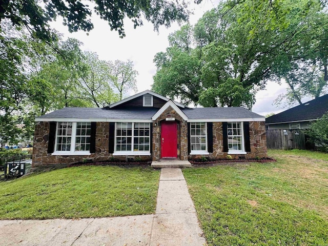 view of front of property featuring fence, stone siding, and a front lawn