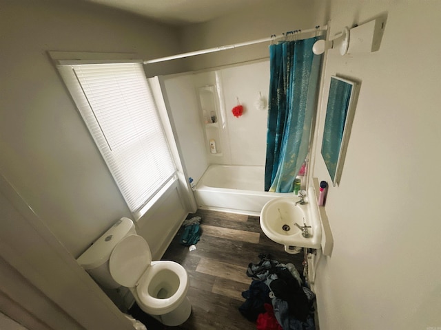 bathroom with shower / bath combo with shower curtain, a sink, wood finished floors, and toilet