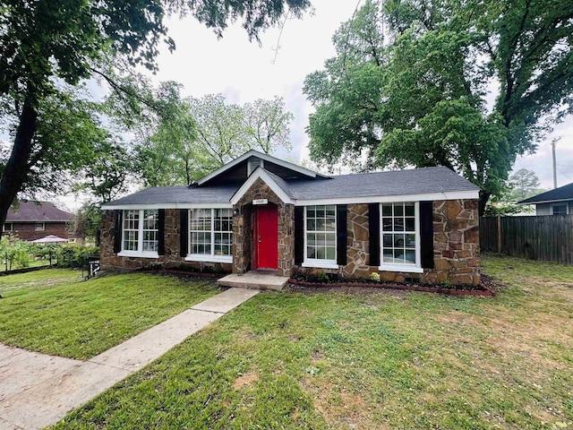 ranch-style home with a front lawn, fence, and stone siding