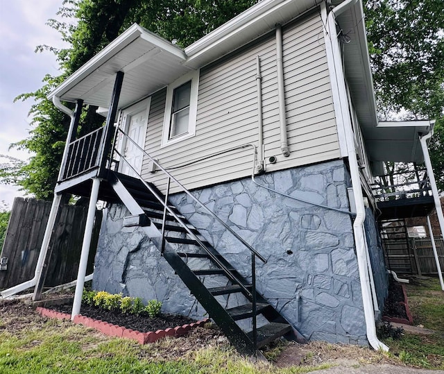 view of property exterior featuring fence and stairs