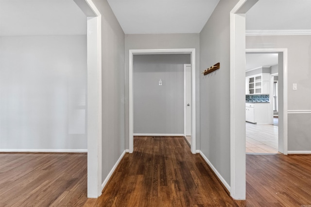 corridor with baseboards and wood finished floors
