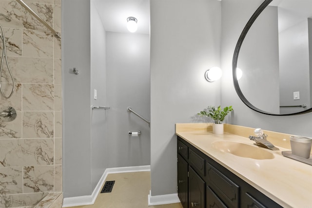full bathroom with baseboards, visible vents, a tile shower, and vanity