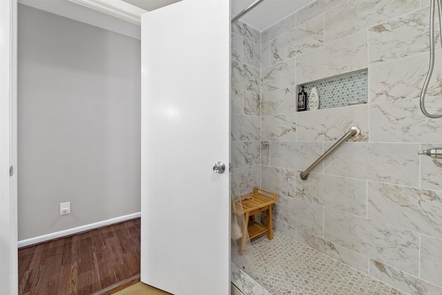 full bathroom featuring baseboards, wood finished floors, and a tile shower