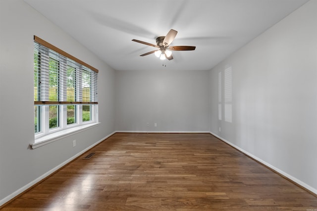 unfurnished room with baseboards, a ceiling fan, wood finished floors, and visible vents
