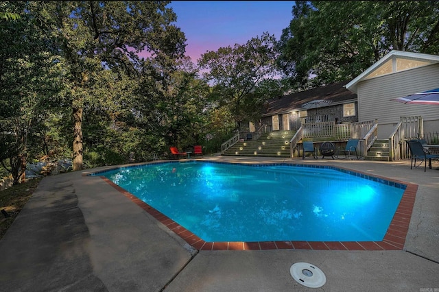 outdoor pool with stairs, a wooden deck, and a patio
