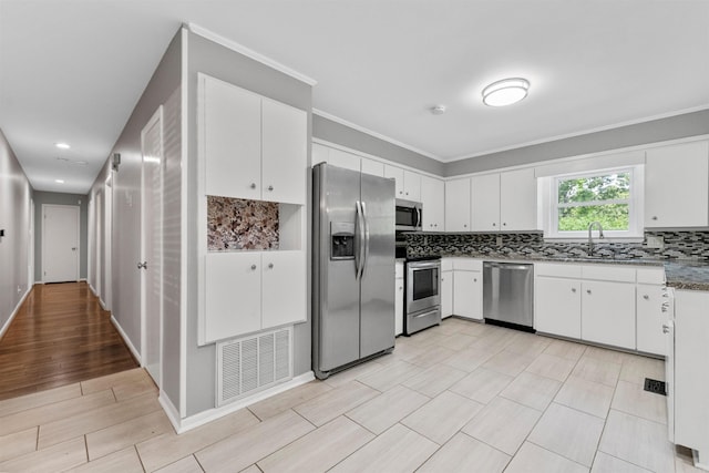kitchen featuring visible vents, white cabinets, tasteful backsplash, and stainless steel appliances