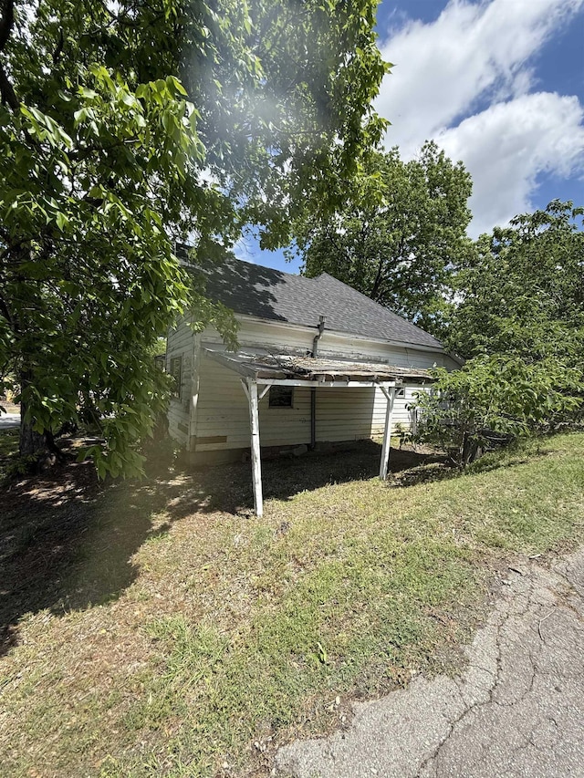 exterior space with roof with shingles and a yard