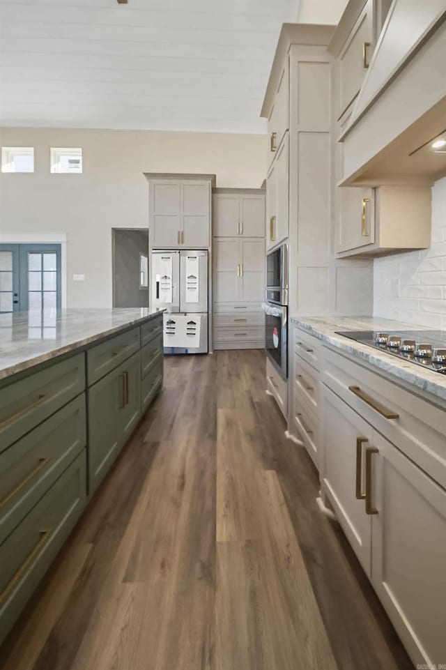 kitchen with light stone counters, black electric stovetop, dark wood finished floors, decorative backsplash, and custom range hood