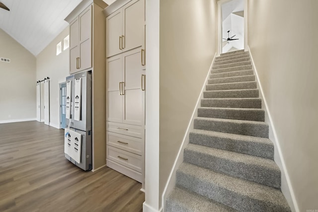 staircase with a ceiling fan, visible vents, wood finished floors, baseboards, and lofted ceiling