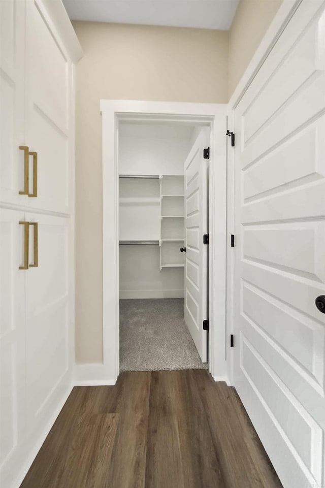 hall featuring dark wood-style flooring and baseboards