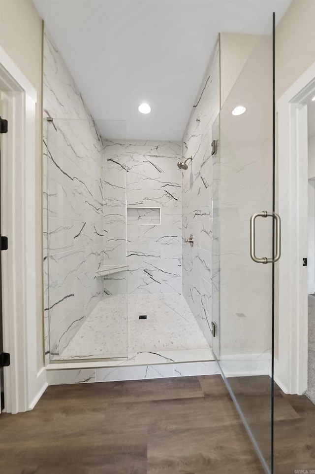 full bath featuring a marble finish shower, recessed lighting, and wood finished floors
