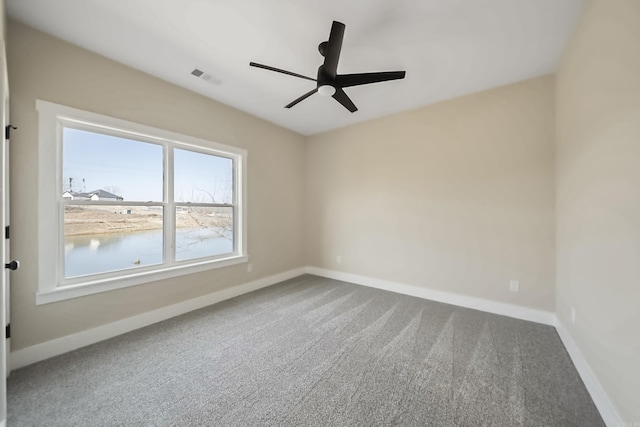 carpeted spare room with baseboards, visible vents, and ceiling fan