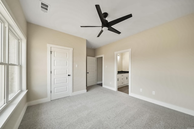 unfurnished bedroom featuring visible vents, baseboards, a ceiling fan, carpet, and ensuite bath
