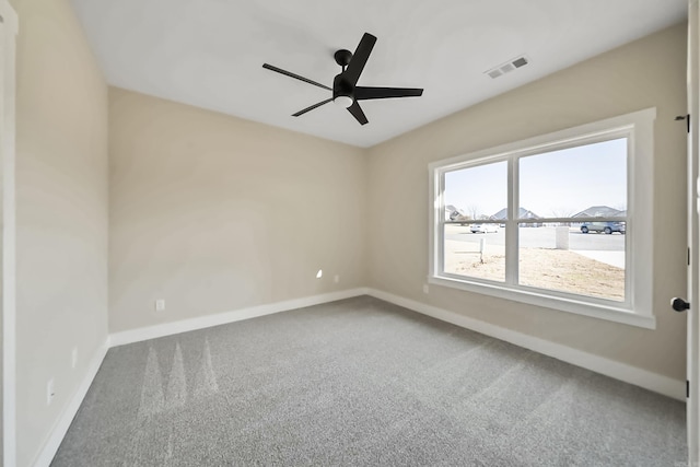 carpeted empty room featuring baseboards, visible vents, and ceiling fan
