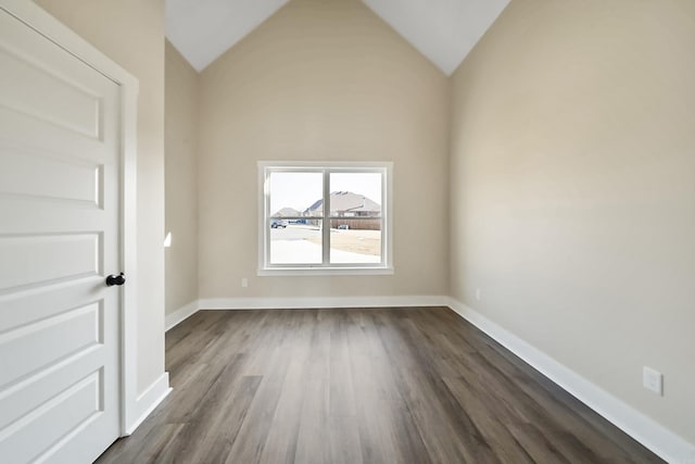 unfurnished room featuring baseboards, lofted ceiling, and dark wood-style floors
