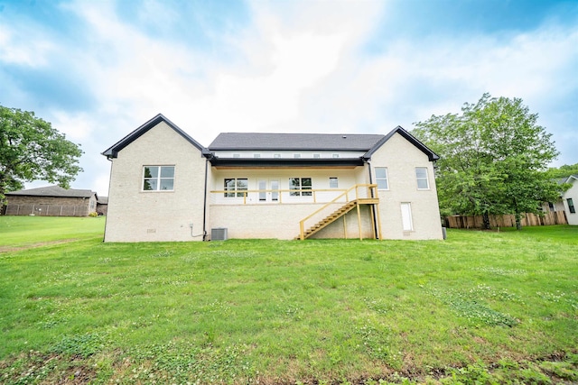 rear view of property with fence, a lawn, and stairway