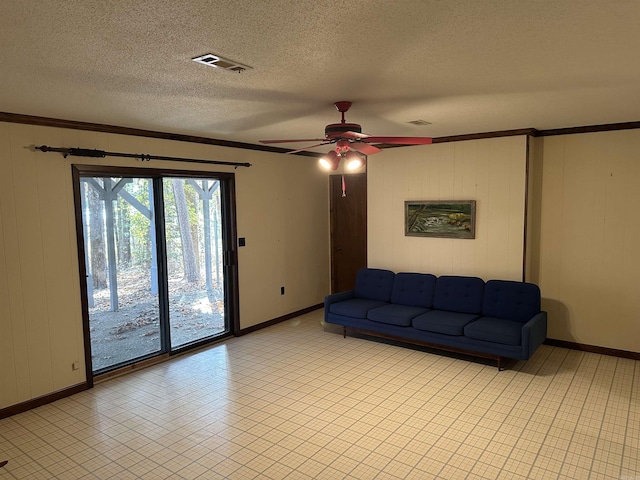 living room with baseboards, a ceiling fan, and crown molding
