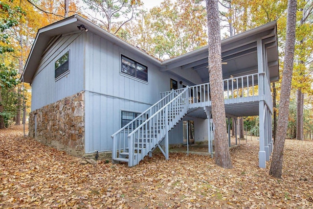 rear view of property featuring stairway and stone siding