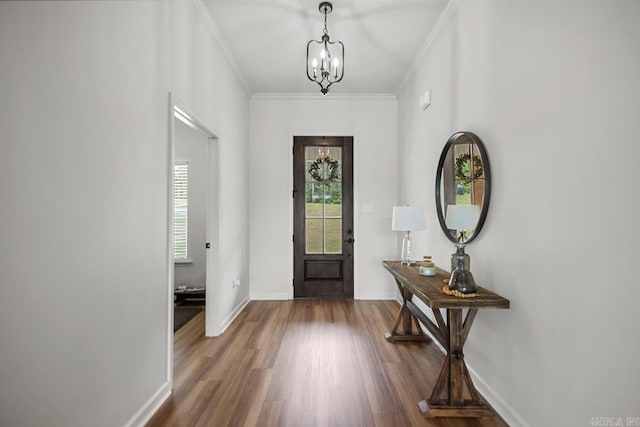 foyer entrance with baseboards, ornamental molding, wood finished floors, and a chandelier
